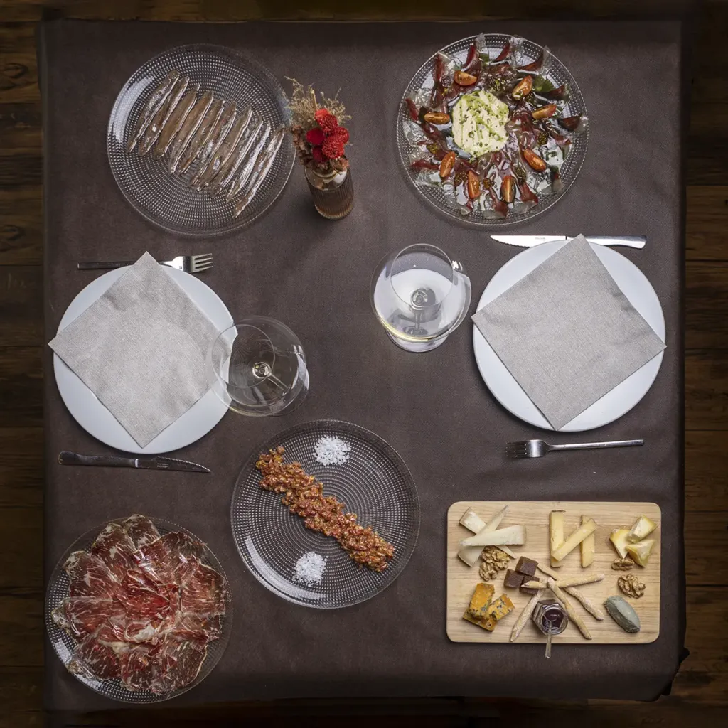 Vista cenital de una mesa con distintos platos: quesos, jamón, ensalada...